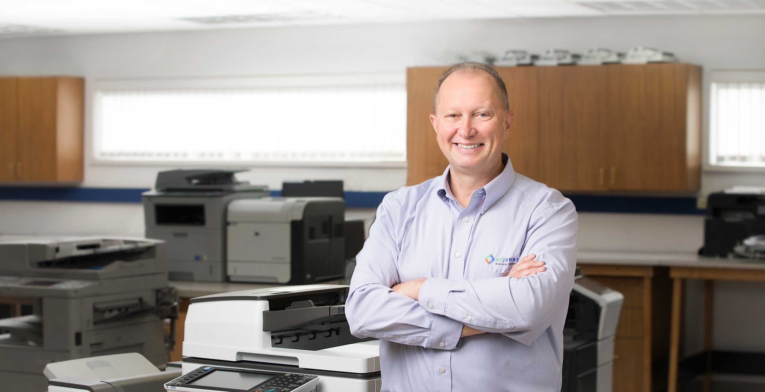 EO Johnson employee smiling next to printer, copier