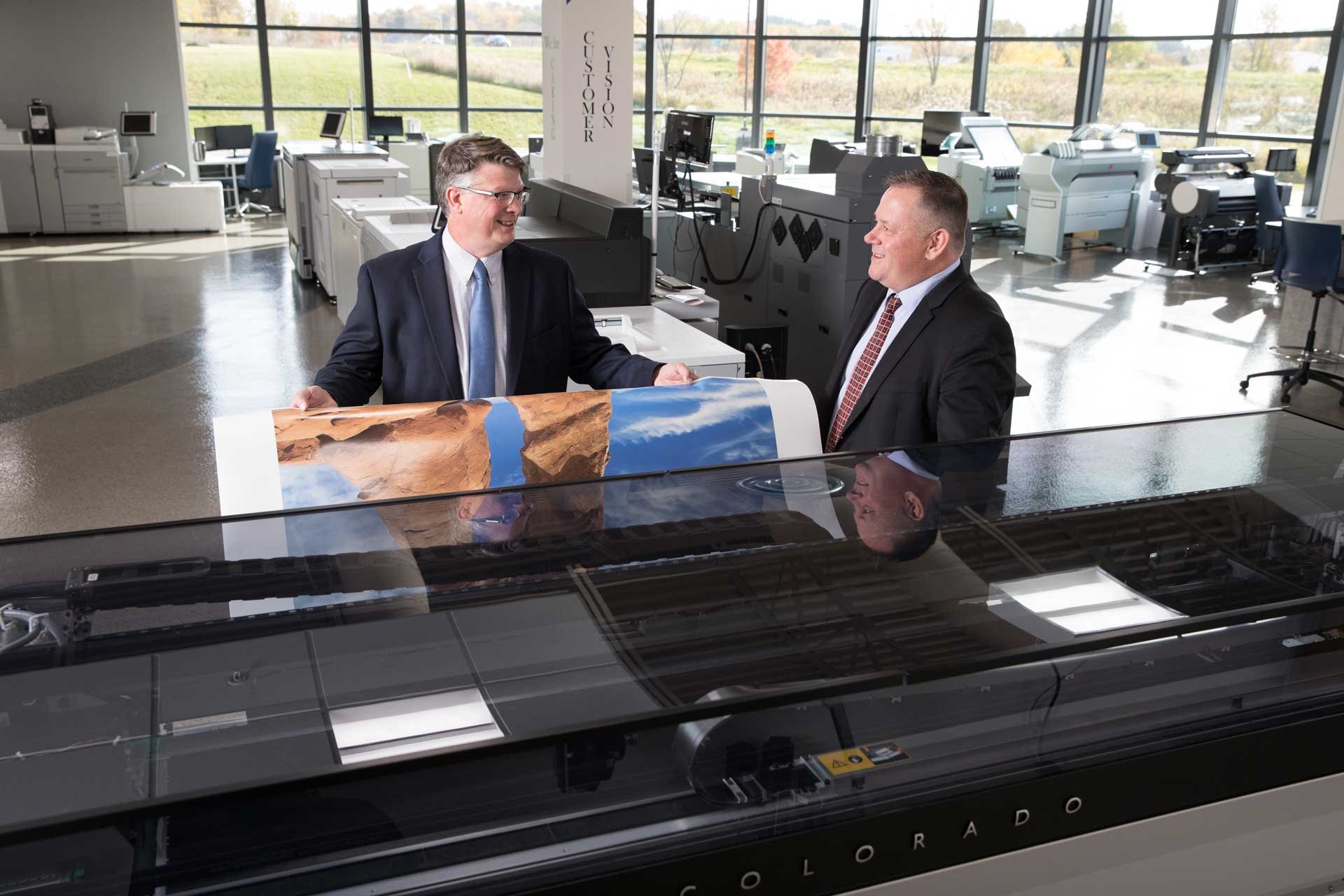 EO Johnson employees next to Colorado wide format printer