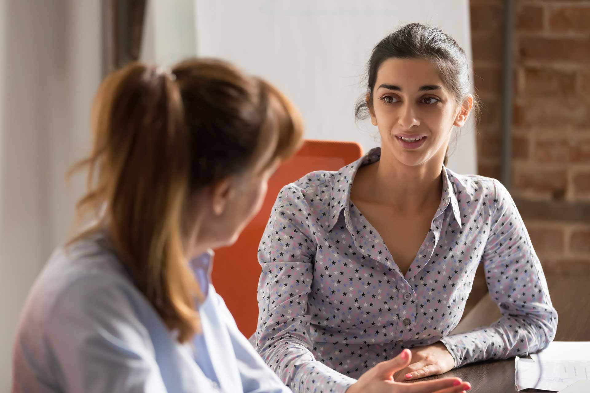 two_business_women_having_discussion_at_table