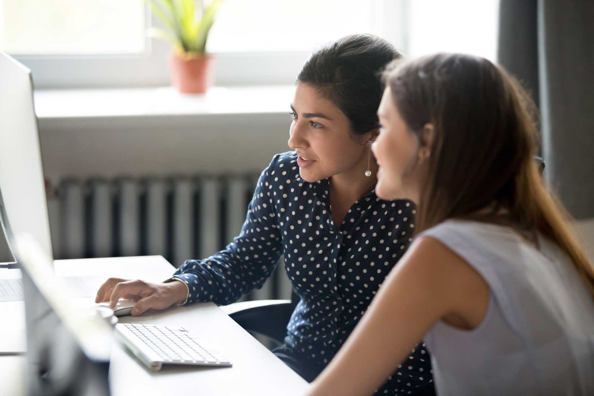 two_women_in_office_working_together_at_desk