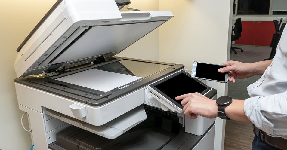 an image of a multifunction printer being used to scan a document in an office setting 