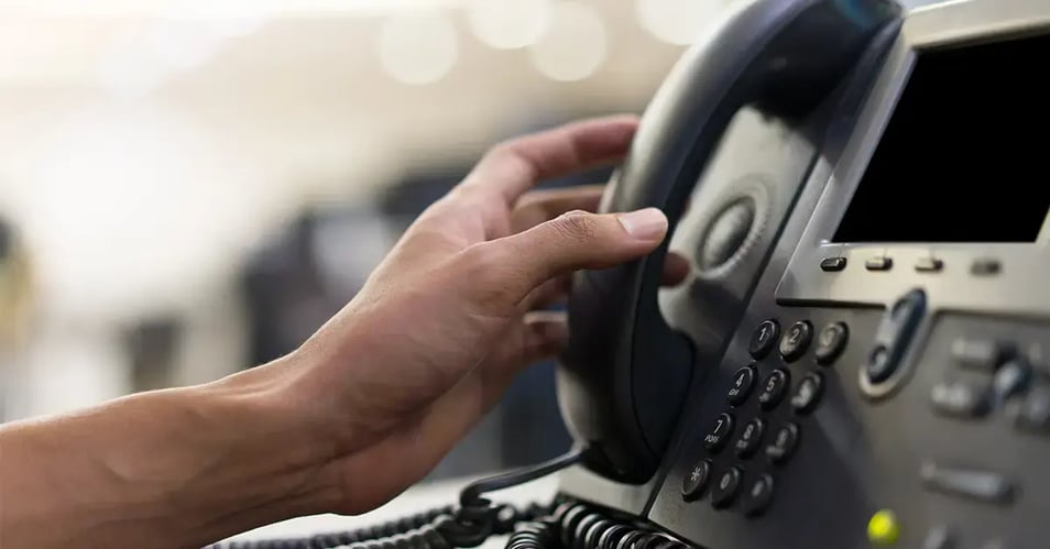 an image of someone picking up the phone at their desk 