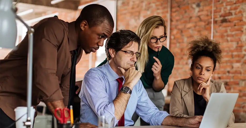 an image of a group of coworkers around a laptop evaluating business processes 