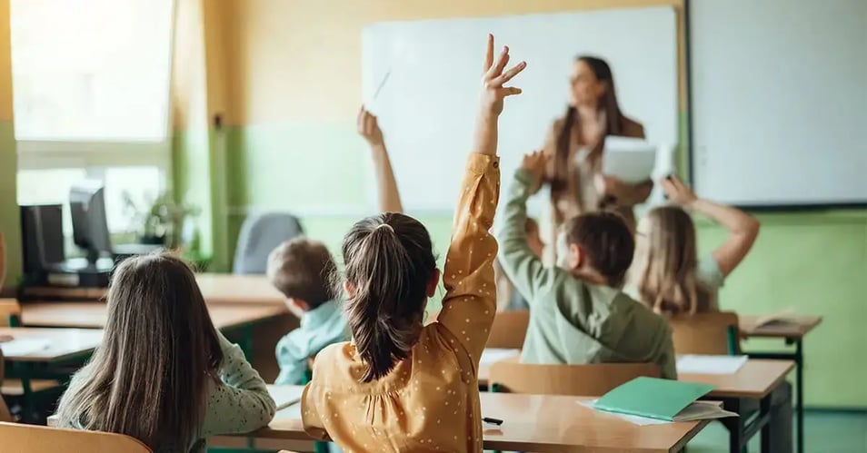 image of students raising their hands in a classroom