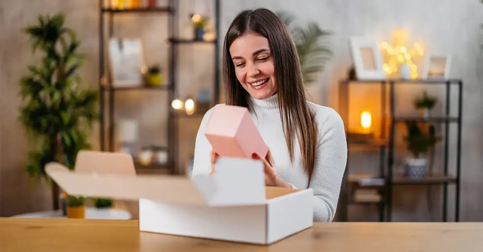 Customer smiling while opening a product package at home, demonstrating how immersive unboxing experiences and premium packaging build brand loyalty.