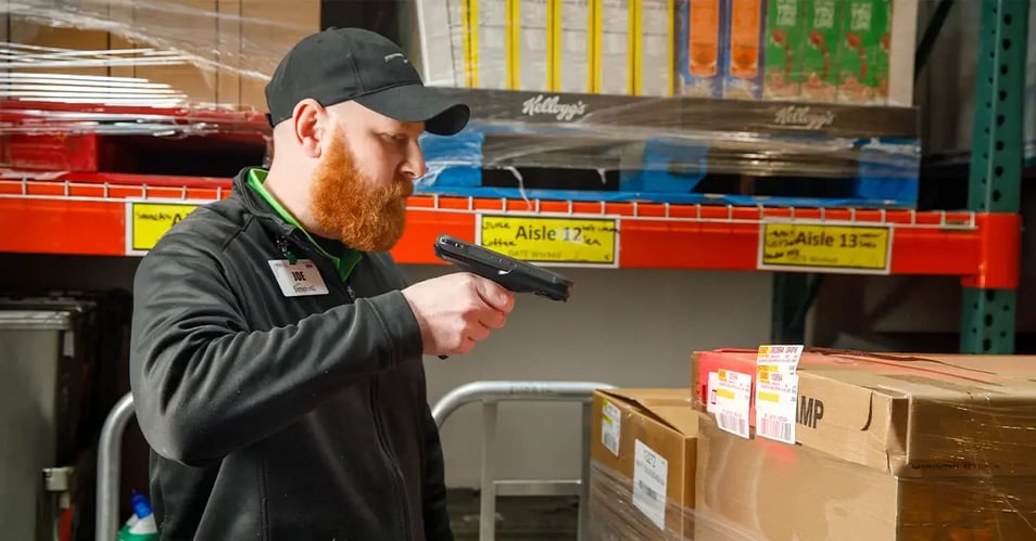 A warehouse employee using a handheld scanner to manage inventory, illustrating the technology supported by a mobile computing partner.
