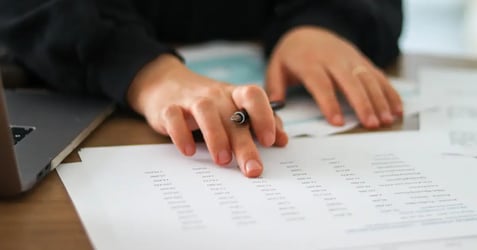 Employee manually cross-referencing invoice data by hand, the exact bottleneck accounts payable automation eliminates