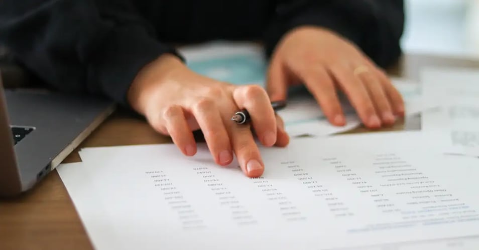 Employee manually cross-referencing invoice data by hand, the exact bottleneck accounts payable automation eliminates