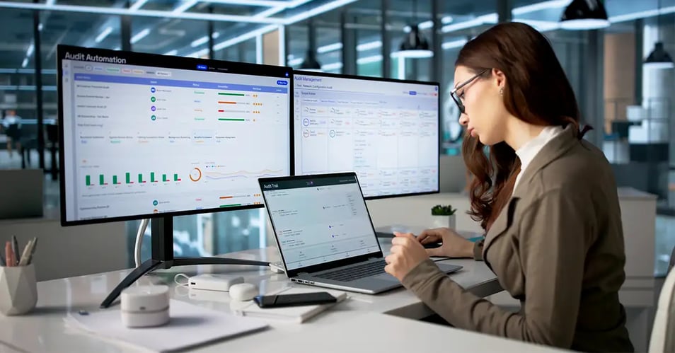 Professional reviewing audit automation dashboards on dual monitors, illustrating how document management system security keeps records audit-ready