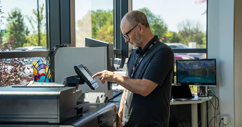 An EO Johnson technician operates the control panel of a production printer, demonstrating an in plant printing solution at the Customer Experience Center.