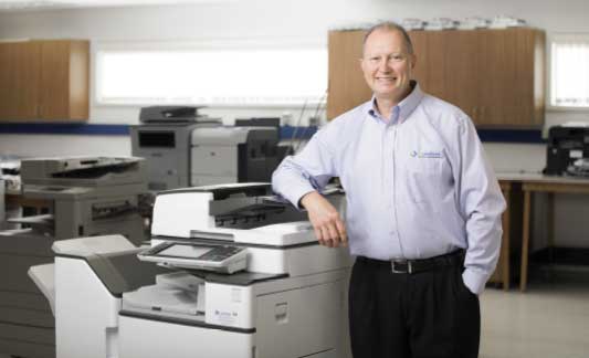 EO Johnson employee next to copier, printer