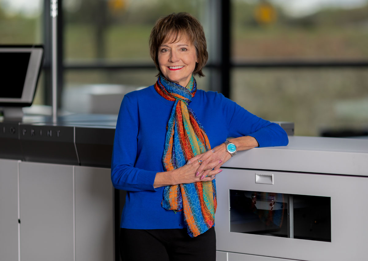 Owner, Mary Jo Johnson, next to wide format printer