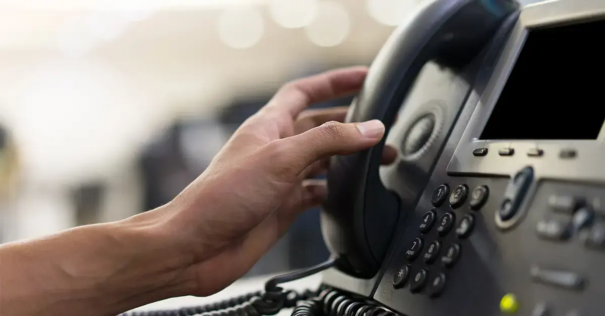 an image of someone picking up the phone at their desk 