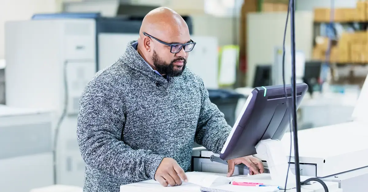 A print production manager using a digital interface to manage a hybrid print workflow in a modern commercial printing facility.