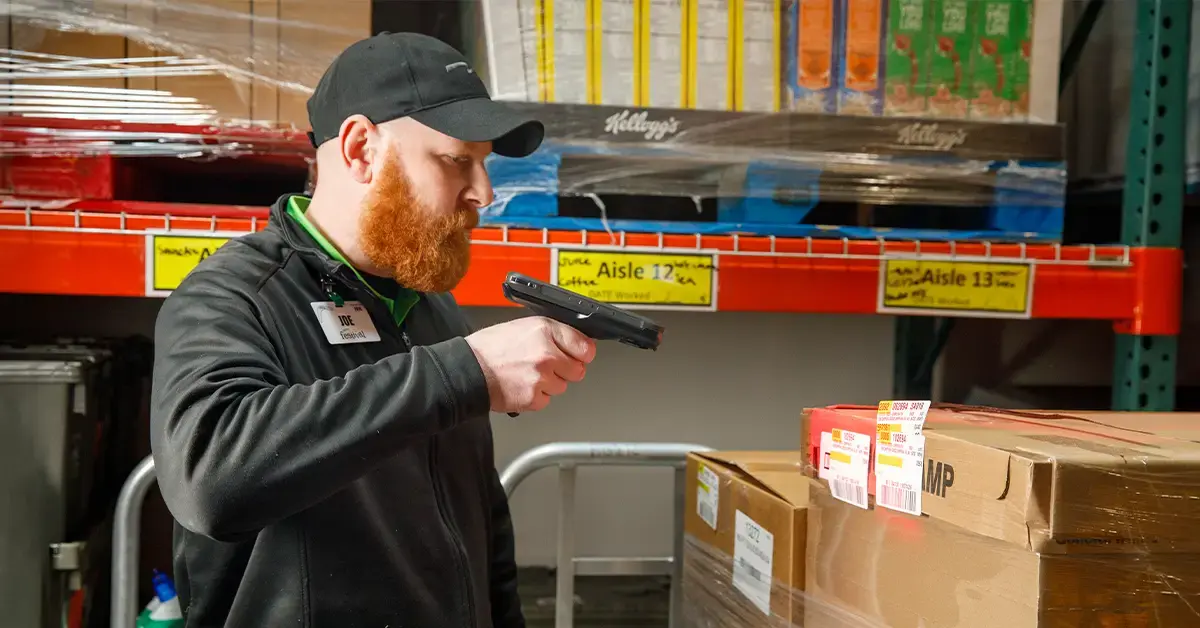 A warehouse employee using a handheld scanner to manage inventory, illustrating the technology supported by a mobile computing partner.