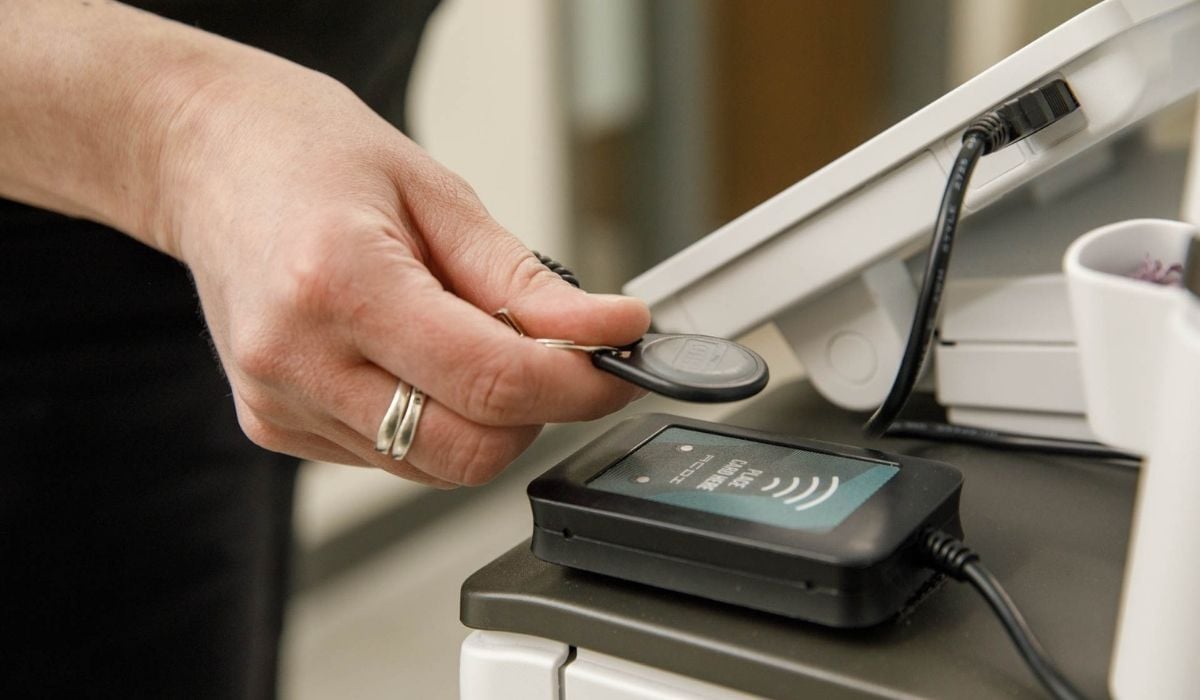 Employee using an NFC key fob to authenticate at a printer before releasing a print job, demonstrating secure release printing as a cloud print security control